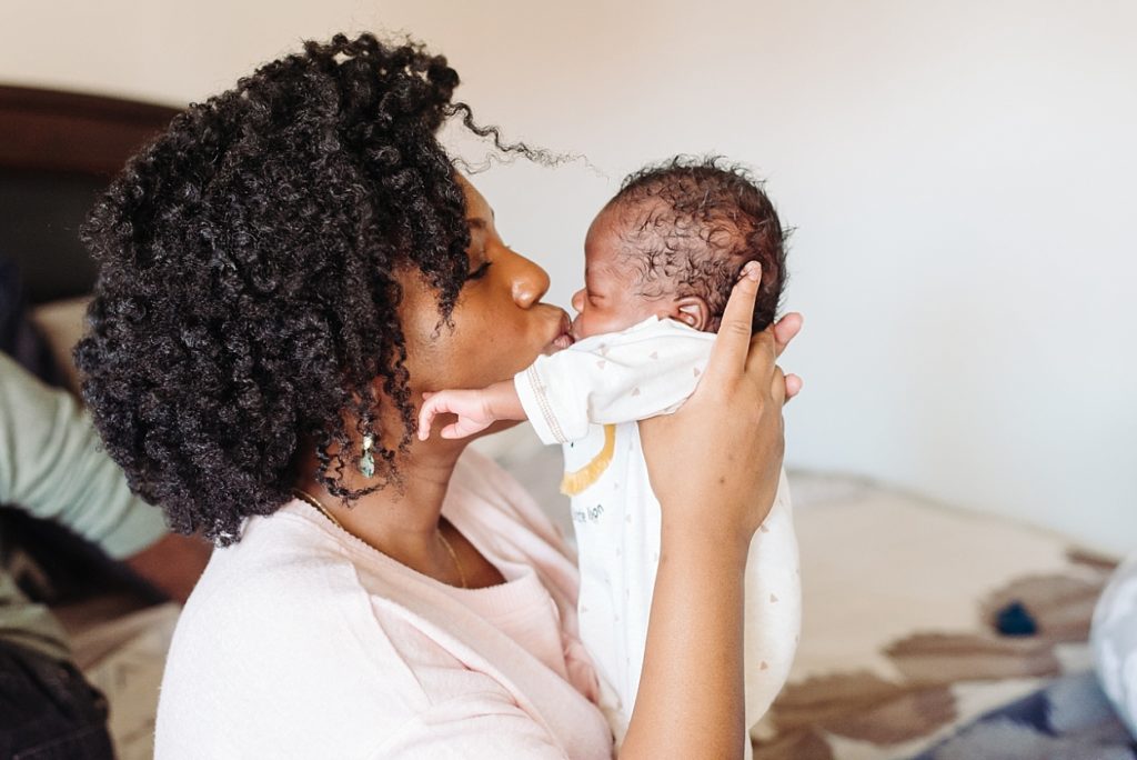 black mother kissing beautiful newborn baby