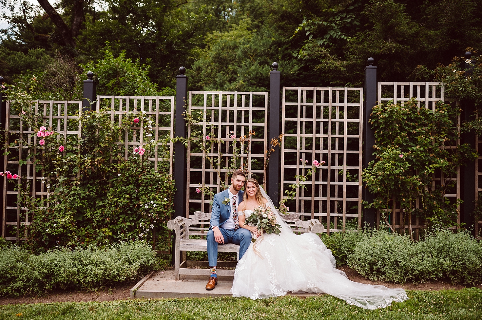 bride and groom sitting on bench in morris arboretum