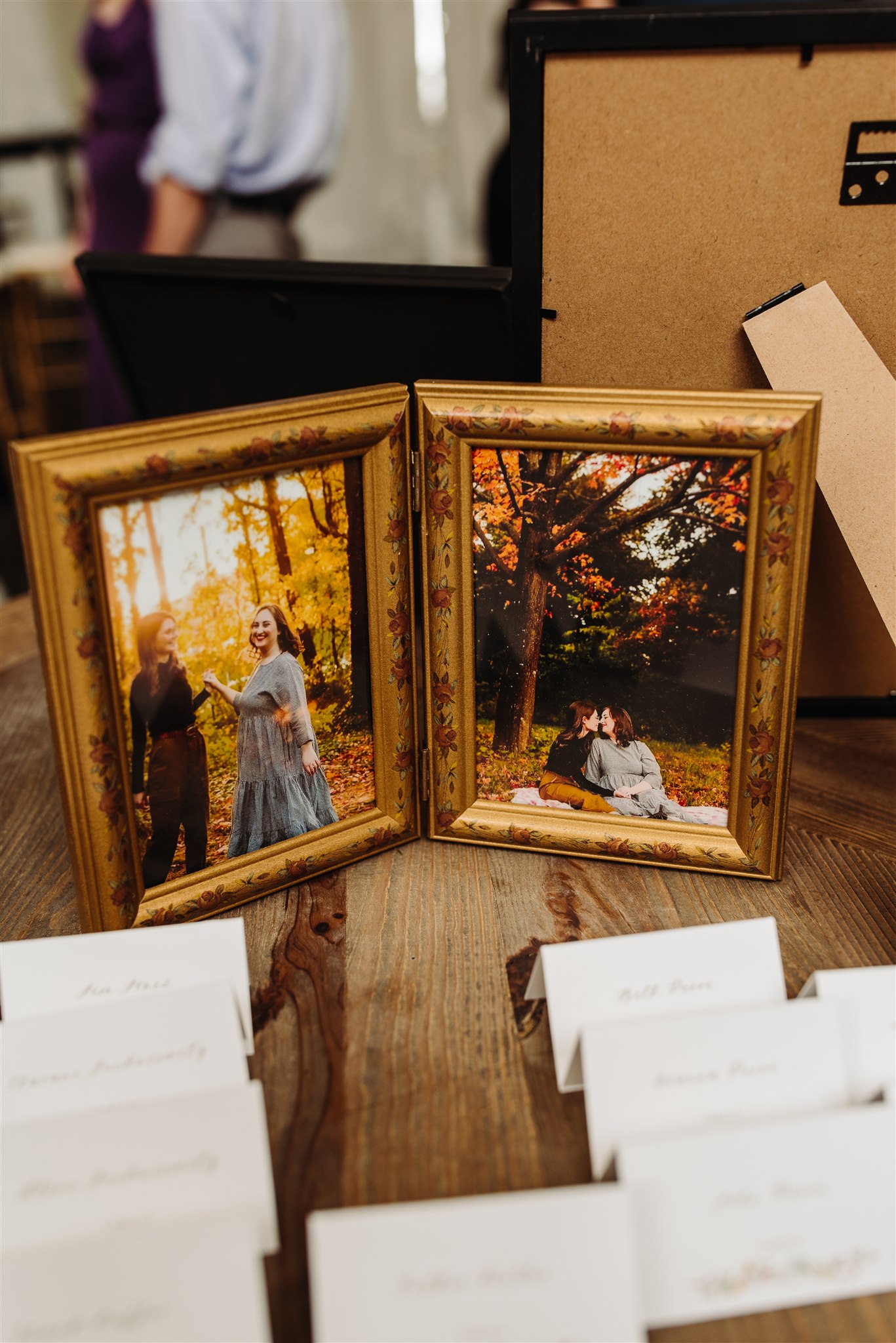 Two framed autumn photographs and name cards on a wooden table.