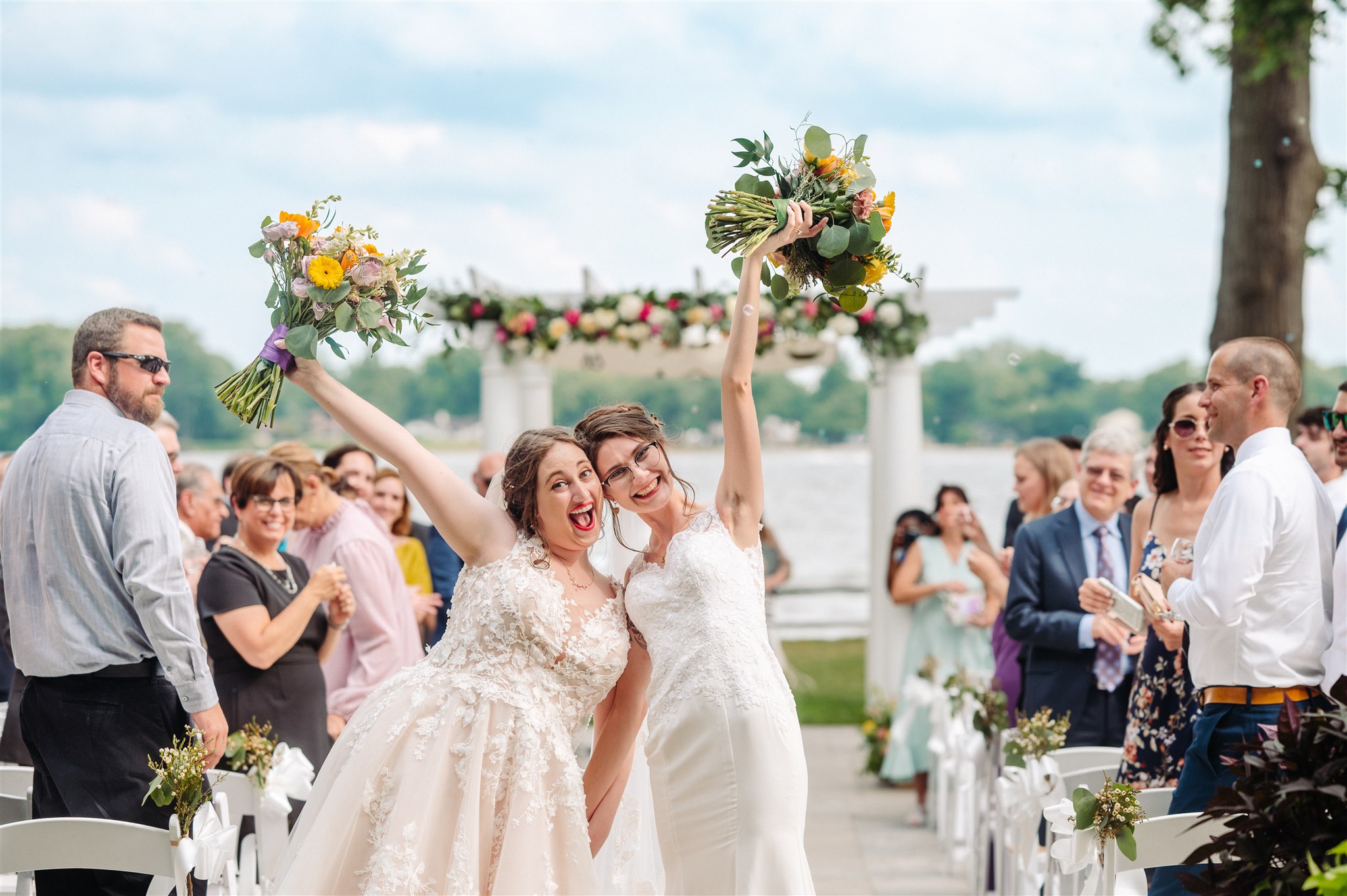 queer jewish couple under floral chuppah at pen ryn estate: partners standing beneath a beautifully decorated canopy, embracing tradition.