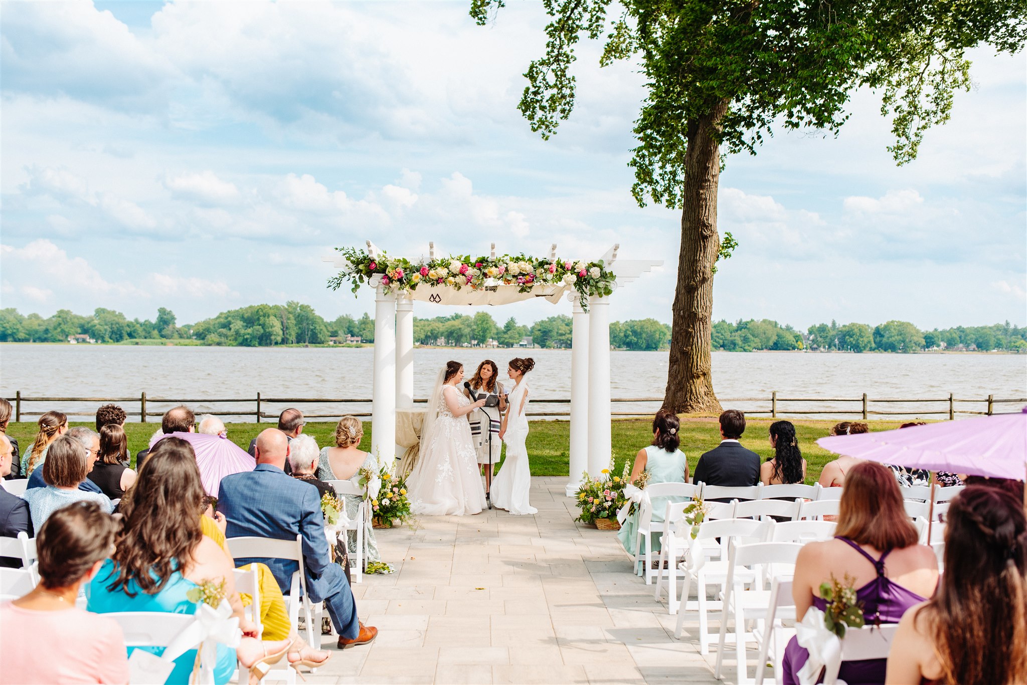 brides holding hands under chuppah with officiant: a moment of unity and commitment.