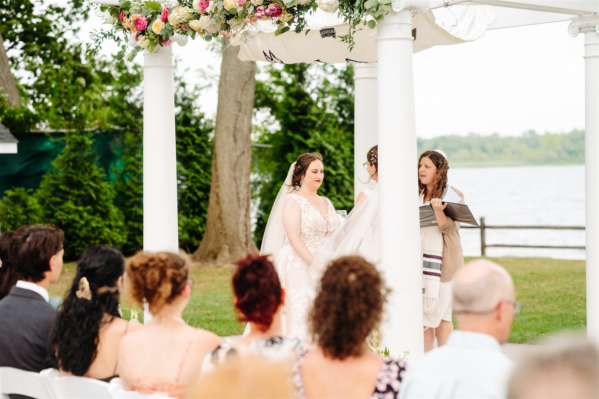 wide shot of outdoor ceremony at river's edge: guests seated along the Delaware River, witnessing the union.